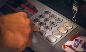 Dłoń wpisująca PIN na klawiaturze bankomatu.