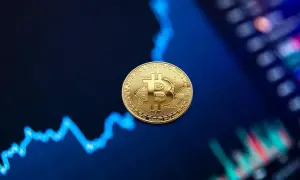 Złota moneta Bitcoin na tle wykresu finansowego.