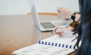 Kiedy wezwanie do zapłaty jest nieważne, warto to zanotować. Dwie osoby pracują przy biurku, jedna pisze w notatniku, druga korzysta z telefonu.