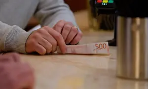 Dłoń trzyma banknot 500 koron szwedzkich. W tle terminal płatniczy. Tak jak obligacje można sprzedać przed terminem ich wykupu przez emitenta, tak i pieniądze można wydać.