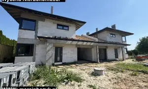 Budowa domu z białych pustaków, widoczne okna i dach. Na dole logo i dane kontaktowe.