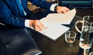 Mężczyzna w garniturze podpisuje dokumenty dotyczące wypłaty środków z PPE po ustaniu zatrudnienia.