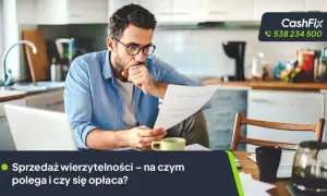 Mężczyzna w okularach analizuje dokumenty przy biurku, obok laptop i filiżanka.