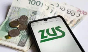 Złote banknoty i monety na nich leżący smartfon z logo ZUS.