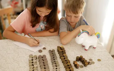 Dzieci liczą monety przy skarbonce w kształcie jednorożca. To świetny sposób na naukę oszczędzania, jak na nest bank konto dla dziecka.