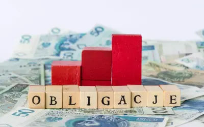 Drewniane klocki z napisem "OBLIGACJE" na tle polskich banknotów. Czy obligacje skarbowe są bezpieczne?
