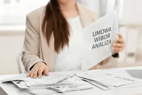 Kobieta w marynarce przegląda dokumenty z napisem "Umowa WIBOR Analiza".