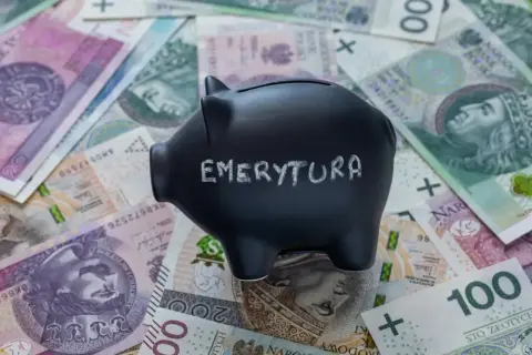 Czarna skarbonka z napisem "EMERYTURA" na tle polskich banknotów.