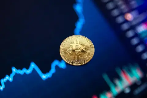 Złota moneta Bitcoin na tle wykresu finansowego.
