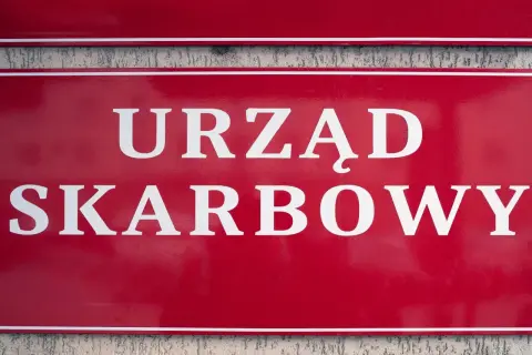 Czerwona tablica z białym napisem "URZĄD SKARBOWY". Współwłaściciel konta bankowego a urząd skarbowy - ważne sprawy podatkowe.