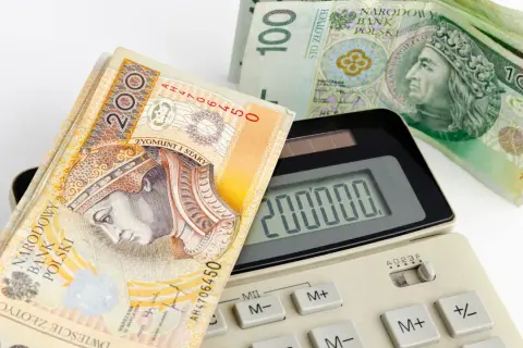 Kalkulator pokazuje 200 000, a obok leżą banknoty 200 i 100 zł. Zastanawiasz się, jaka rata kredytu 50 tys. Cię czeka?