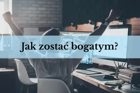 Mężczyzna z rękami w górze siedzi przy biurku z komputerem, na którym widać wykresy.