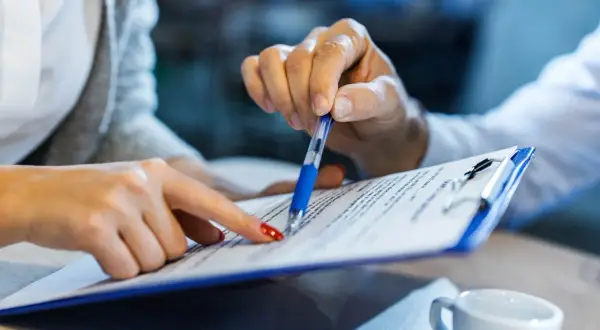Dwie osoby analizują dokumenty, być może szukając informacji, jak zamknąć konto w BNP Paribas.