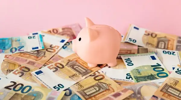 Różowa świnka-skarbonka na stosie banknotów euro. Zastanawiasz się nad boś bank konto oszczędnościowe oprocentowanie?
