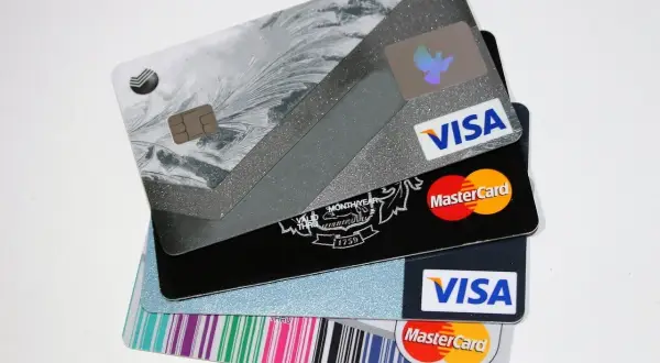Stos kart kredytowych Visa i Mastercard z różnymi wzorami.