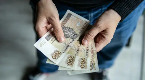 Dłonie trzymające kilka banknotów 200 zł.