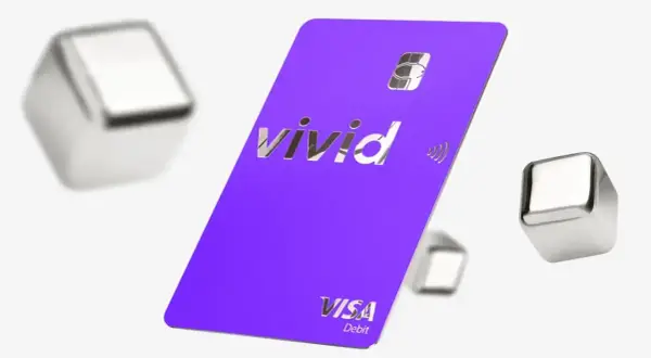 Fioletowa karta Vivid Visa Debit z błyszczącym logo, otoczona metalicznymi sześcianami. Wiele pozytywnych vivid money opinie potwierdza jej funkcjonalność.
