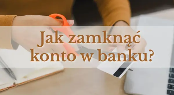 Ręce przecinające nożyczkami kartę bankową na tle laptopa i notatnika.