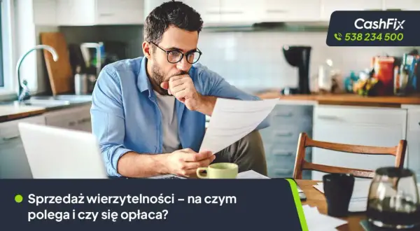 Mężczyzna w okularach analizuje dokumenty przy biurku, obok laptop i filiżanka.
