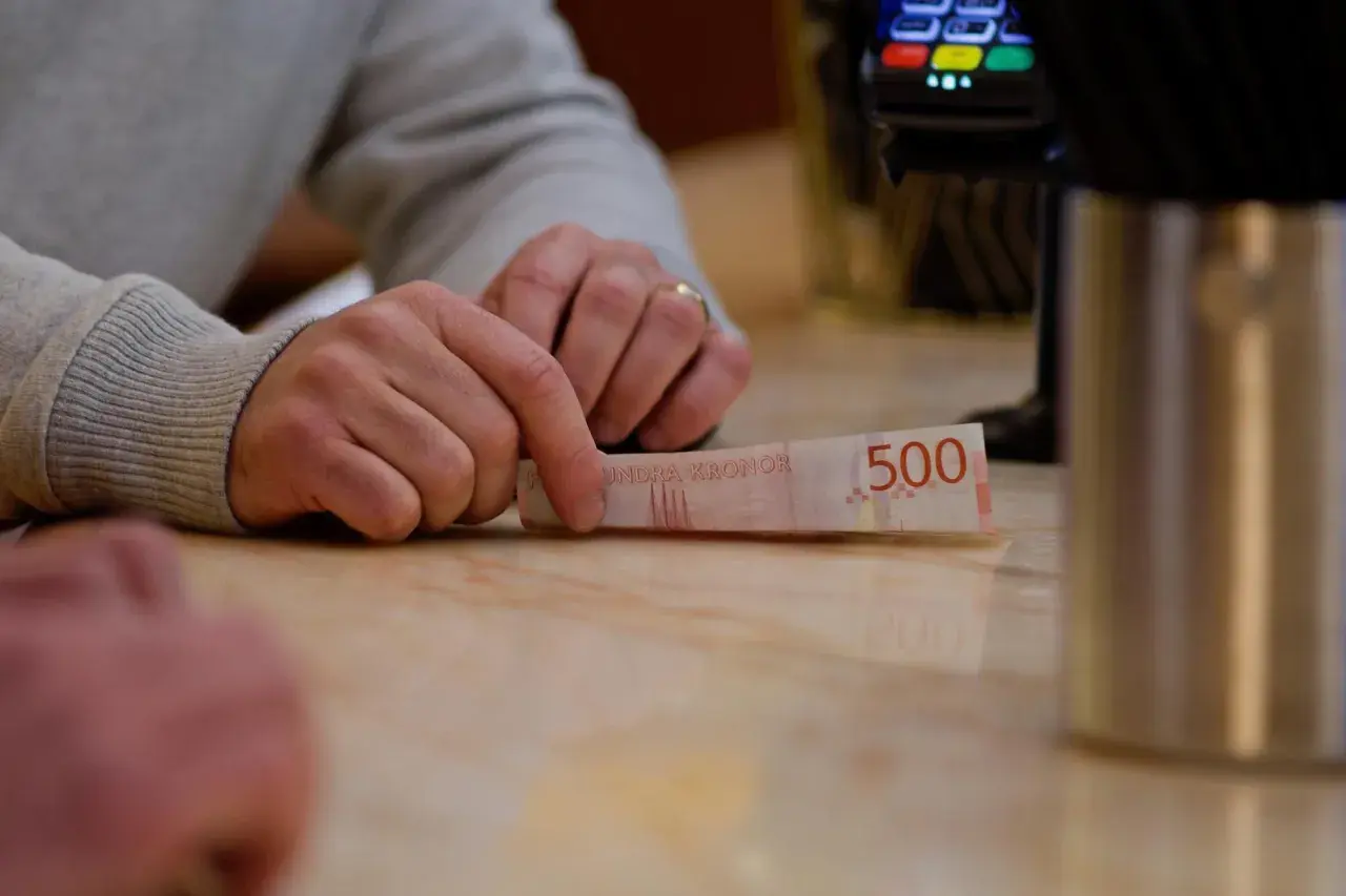 Dłoń trzyma banknot 500 koron szwedzkich. W tle terminal płatniczy. Tak jak obligacje można sprzedać przed terminem ich wykupu przez emitenta, tak i pieniądze można wydać.