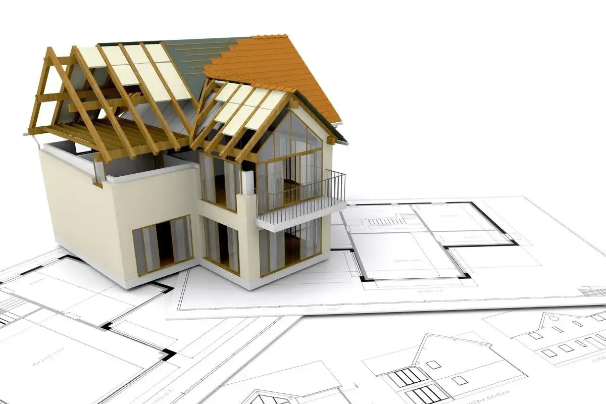 Model domu w budowie na tle planów architektonicznych. Idealny do wizualizacji kredytu na budowę domu.