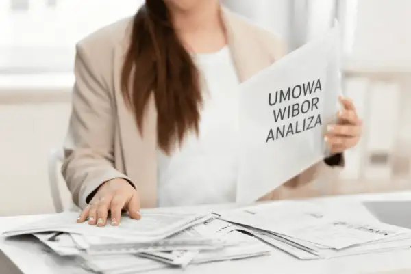 Kobieta w marynarce przegląda dokumenty z napisem "Umowa WIBOR Analiza".