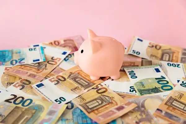 Różowa świnka-skarbonka na stosie banknotów euro. Zastanawiasz się nad boś bank konto oszczędnościowe oprocentowanie?