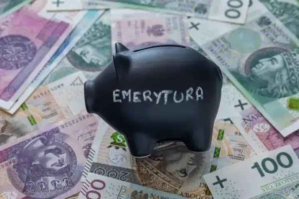 Czarna skarbonka z napisem "EMERYTURA" na tle polskich banknotów.