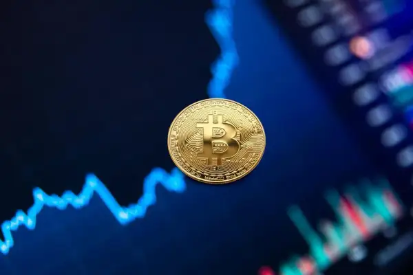 Złota moneta Bitcoin na tle wykresu finansowego.