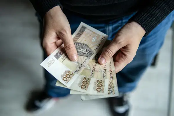 Dłonie trzymające kilka banknotów 200 zł.