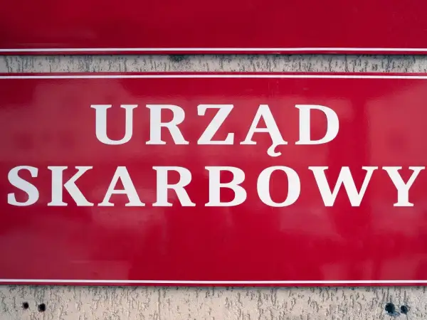 Czerwona tablica z białym napisem "URZĄD SKARBOWY". Współwłaściciel konta bankowego a urząd skarbowy - ważne sprawy podatkowe.