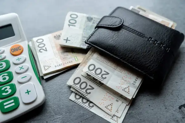 Portfel z polskimi banknotami i kalkulatorem. Rosnąca inflacja w Polsce sprawia, że pieniądze topnieją.