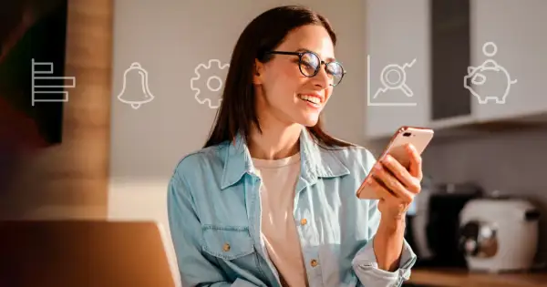 Uśmiechnięta kobieta w okularach trzyma smartfon, na tle ikony finansowe: wykres, dzwonek, koło zębate, lupa, skarbonka.