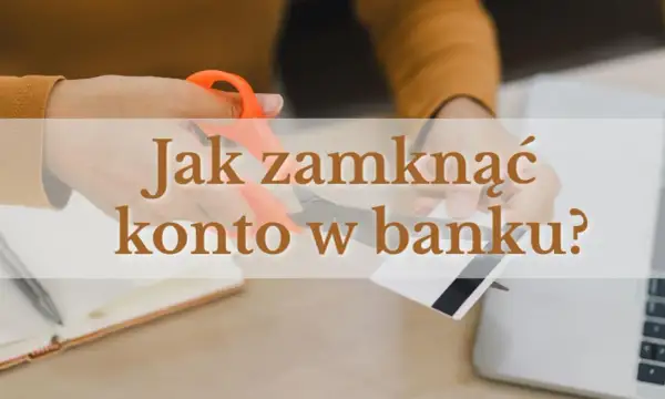 Ręce przecinające nożyczkami kartę bankową na tle laptopa i notatnika.