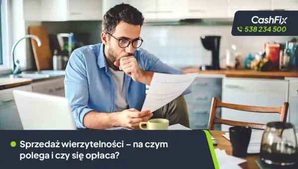 Mężczyzna w okularach analizuje dokumenty przy biurku, obok laptop i filiżanka.