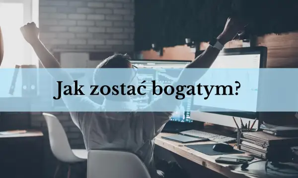 Mężczyzna z rękami w górze siedzi przy biurku z komputerem, na którym widać wykresy.